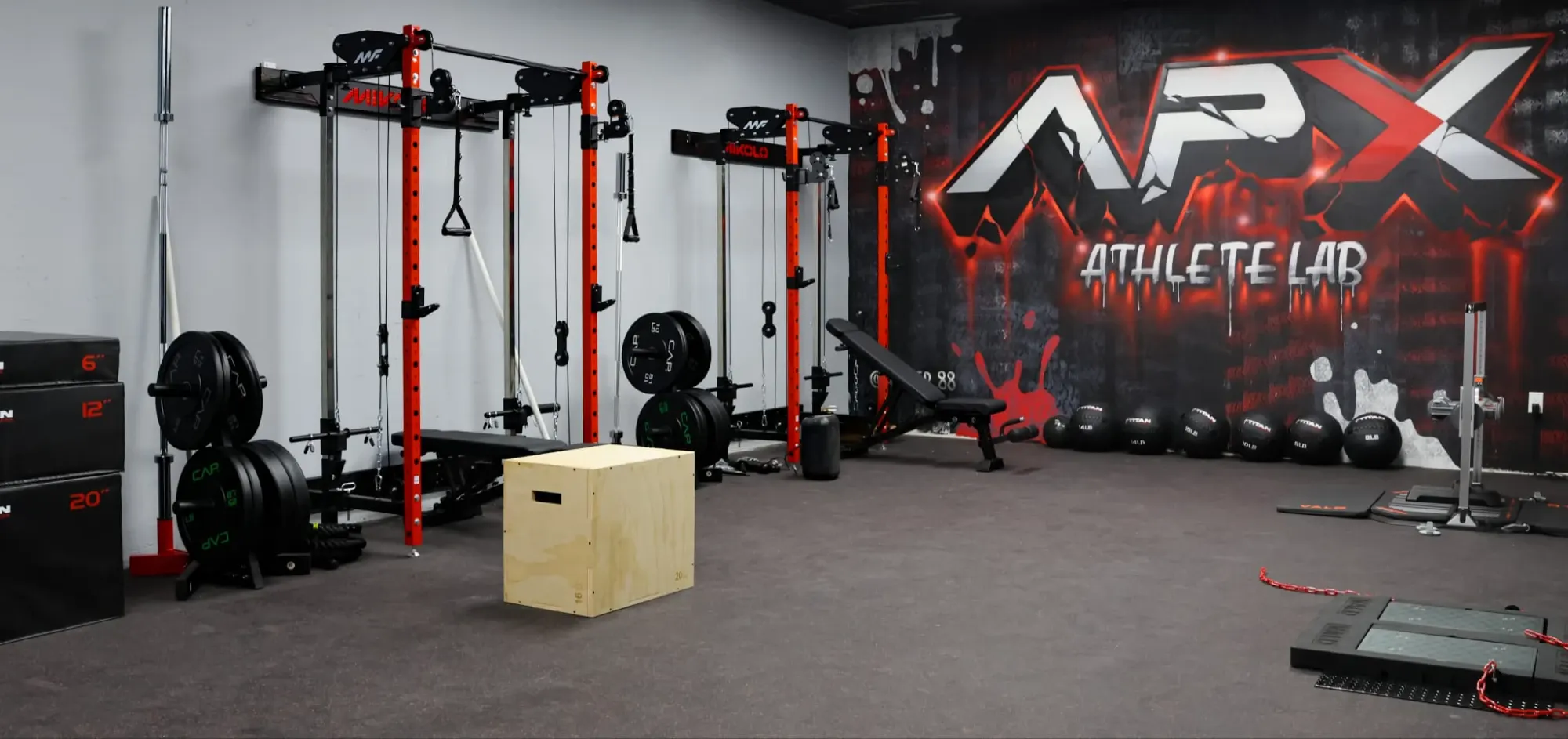 The APX training floor: red racks along the wall, plyo boxes, medicine balls, force plates, and the APX Athlete Lab mural